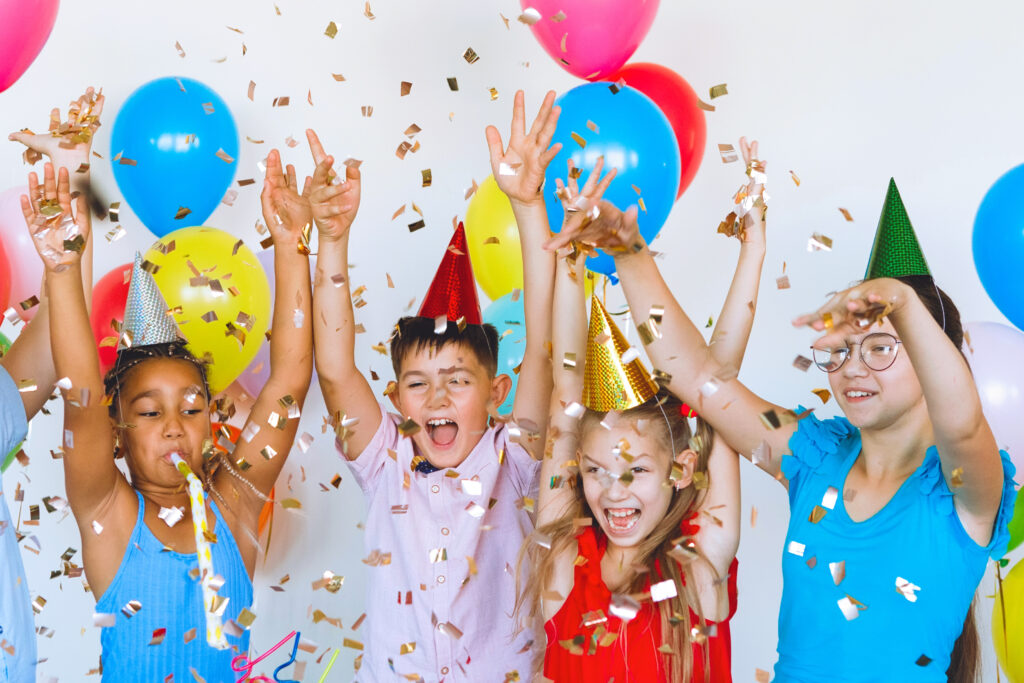 Tweens celebrating a birthday party with confetti and balloons.